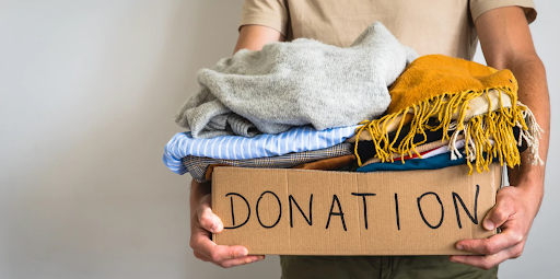 Decluttering Indian Homes: Tips for a Calm & Organized Space 7 Person holding a box of clothes labeled 'Donation.'